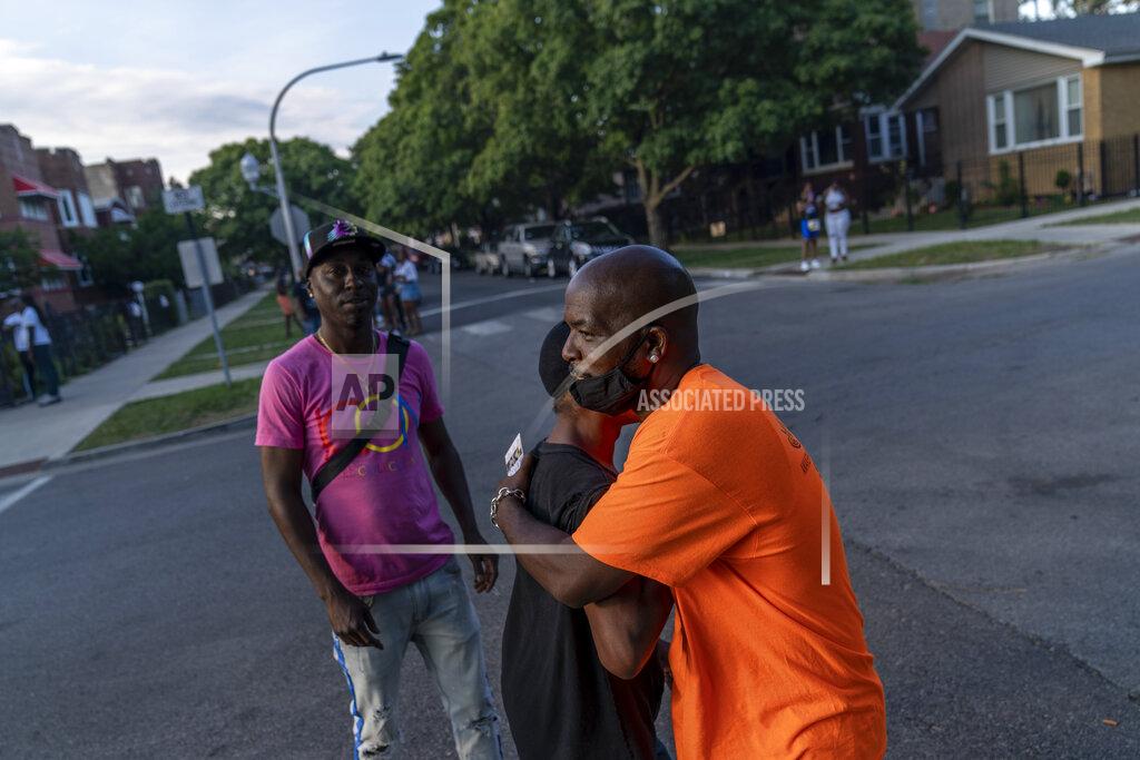David Goldman Demetrius Mingo, right, an outreach worker with the Target Area Development Corporation, a nonprofit that addresses stubborn local problems, embraces an old friend as neighboring blocks attend a 'peace picnic' in the Auburn Gresham neighborhood in Chicago, Saturday, Aug. 22, 2020. The group supplied its outreach workers face masks to distribute while making their rounds to prevent gang retaliation. It hasn't been easy making the argument to young men who pay little attention to the virus and already have a fatalistic view of life, says Autry Phillips, the group's executive director. (AP Photo/David Goldman)