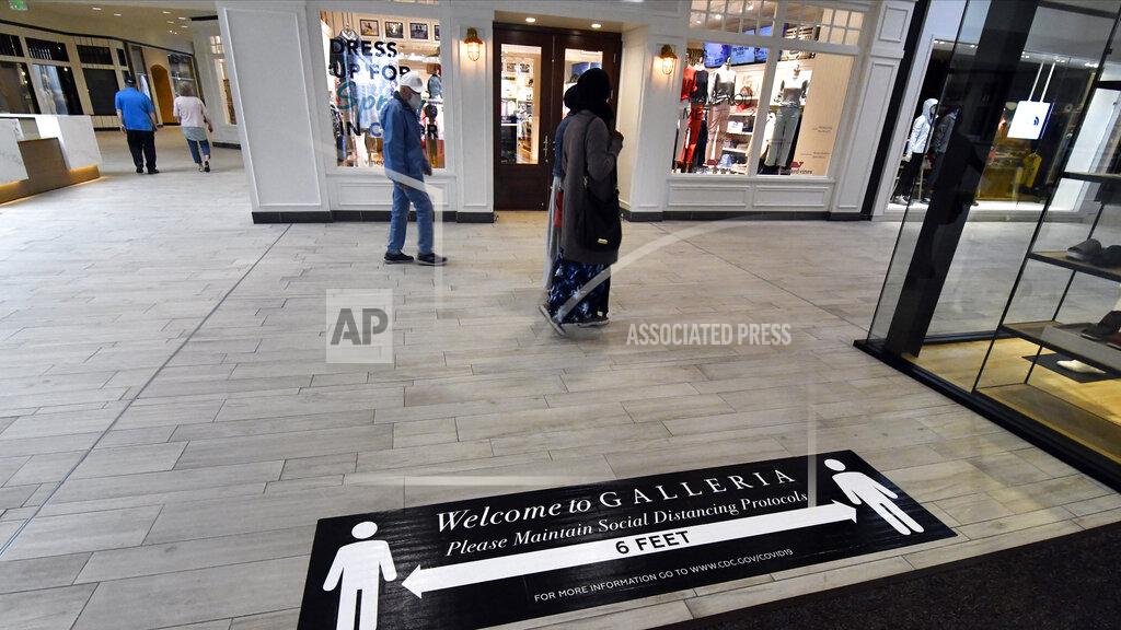 Jim Mone Visitors walk by one of the stores in the Galleria which reopened Monday, May 18, 2020 in Edina, Minn. (AP Photo/Jim Mone)