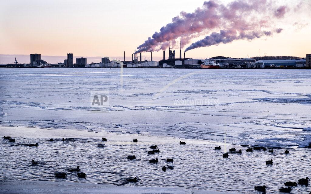 Henning Bagger Cold morning by the Limfjord body of water covered by ice in Aalborg, Denmark, Friday Feb. 12 2021, with the the cement factory Roerdal's chimneys in background. In Aalborg the temperatures were around minus 15 degrees overnight. (Henning Bagger / Ritzau via AP)