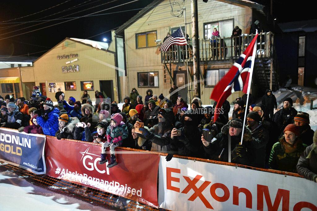 FILE - In this March 18, 2020, file photo, a crowd standing behind ExxonMobile signage watches as Thomas Waerner, of Norway, arrives in Nome, Alaska to win the Iditarod Trail Sled Dog Race. The world's most famous sled dog race has lost another major sponsor as the Iditarod prepares for a scaled-back version of this year's race because of the pandemic, officials said Thursday, Jan. 21, 2021. ExxonMobil confirmed to The Associated Press that the oil giant will drop its sponsorship of the race. (Marc Lester/Anchorage Daily News via AP, File)