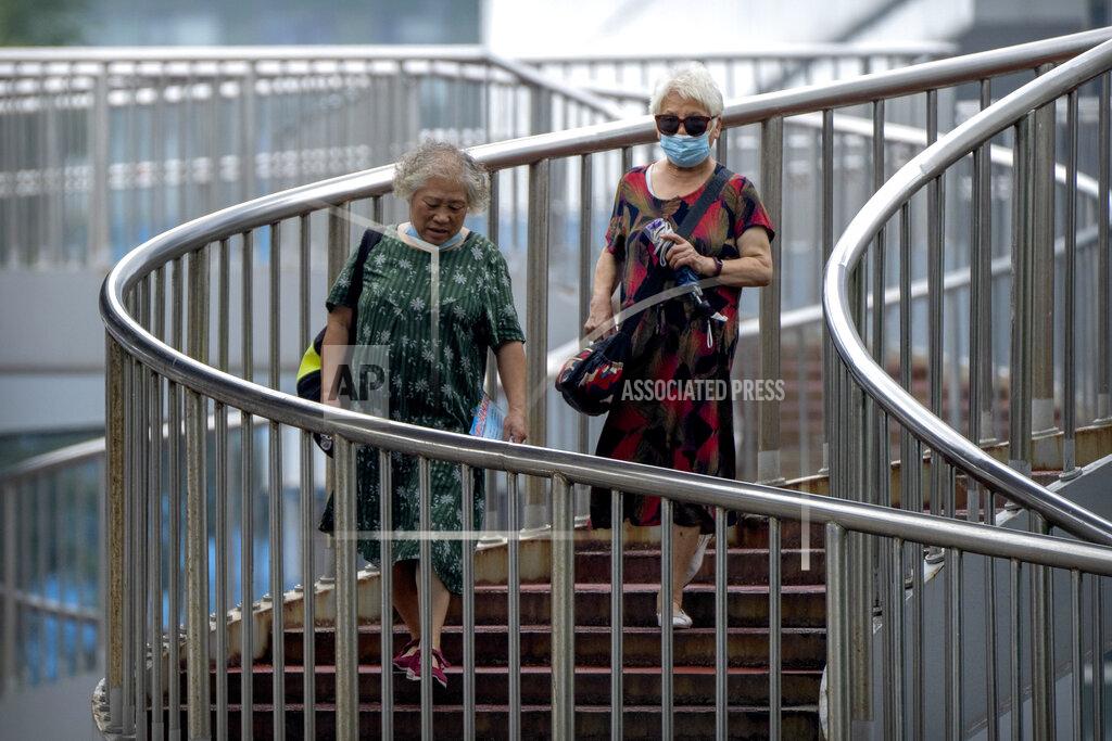 Mark Schiefelbein People wearing face masks to protect against COVID-19 walk down a staircase on a pedestrian bridge in Beijing, Wednesday, Aug. 4, 2021. The coronavirus’s delta variant is challenging China’s costly strategy of isolating cities, prompting warnings that Chinese leaders who were confident they could keep the virus out of the country need a less disruptive approach. (AP Photo/Mark Schiefelbein)
