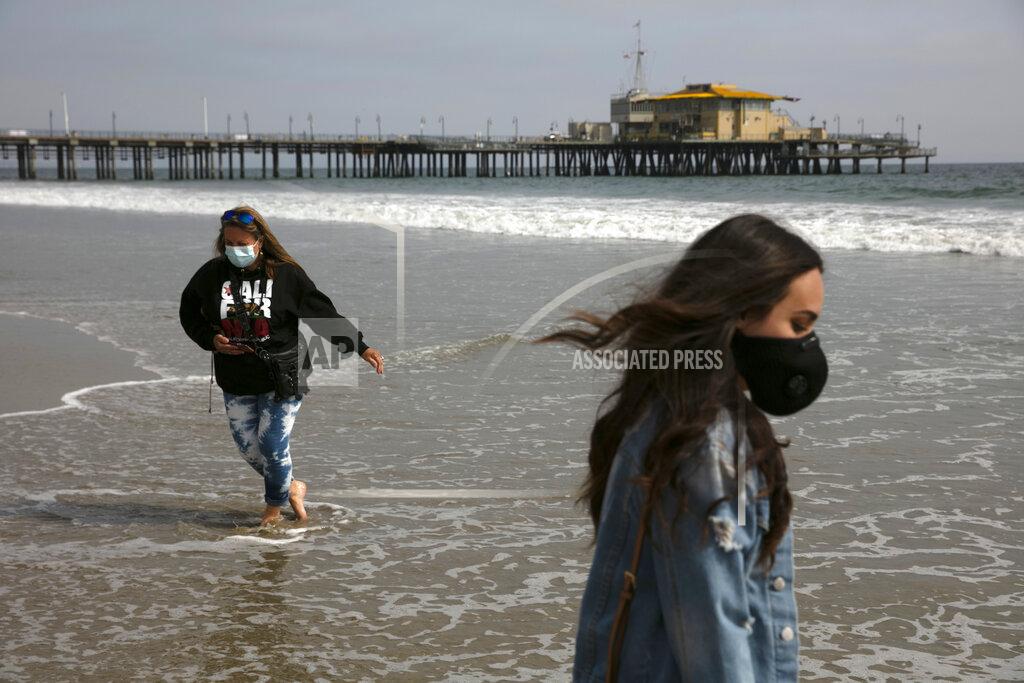 Jae C. Hong FILE - In this June 23, 2020, file photo, Malia Pena, foreground, and her mother, Lisa Torriente, wear masks as they visit the beach in Santa Monica, Calif. (AP Photo/Jae C. Hong, File)