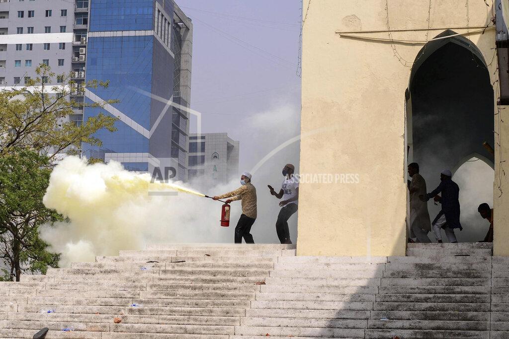 Mahmud Hossain Opu A group of protestors use fire extinguisher during a clash with another group after Friday prayers at Baitul Mokarram mosque in Dhaka, Bangladesh, Friday, March 26, 2021. Witnesses said violent clashes broke out after one faction of protesters began waving their shoes as a sign of disrespect to Indian Prime Minister Narendra Modi, and another group tried to stop them. Local media said the protesters who tried to stop the shoe-waving are aligned with the ruling Awami League party. The party criticized the other protest faction for attempting to create chaos in the country during Modi’s visit. (AP Photo/Mahmud Hossain Opu)