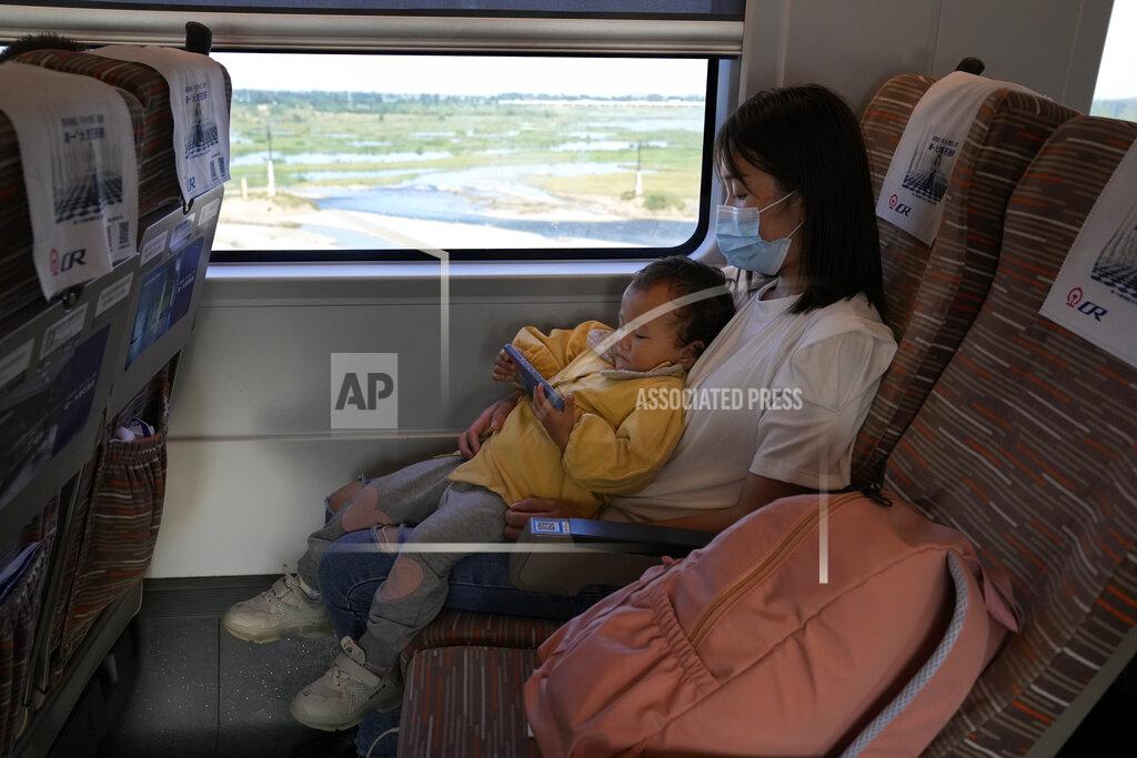 Ng Han Guan A child plays with a smartphone on the knees of a woman during a high speed train from Henan to Beijing Wednesday, Sept. 15, 2021. China has set new rules limiting the amount of time kids can spend playing online games. (AP Photo/Ng Han Guan)