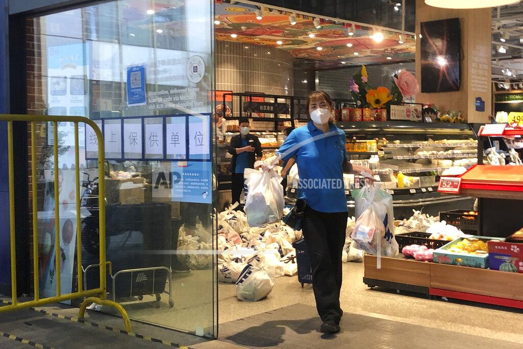 Chen Si An employee carries bags of groceries for delivery from a supermarket in Shanghai, China, Monday, May 23, 2022. Shanghai reported 480,000 people were still confined to their homes due to COVID-19 precautions, while 1.59 million were permitted to move around their neighborhoods and 21.2 million were under lighter restrictions. (AP Photo/Chen Si)