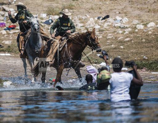FILE - In this Sept. 19, 2021, file photo, U.S. Customs and Border Protection mounted officers attempt to contain migrants as they cross the Rio Grande from Ciudad Acuña, Mexico, into Del Rio, Texas. The Border Patrol's treatment of Haitian migrants, they say, is just the latest in a long history of discriminatory U.S. policies and of indignities faced by Black people, sparking new anger among Haitian Americans, Black immigrant advocates and civil rights leaders.( AP Photo/Felix Marquez, File)