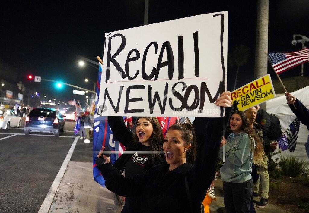 FILE - In this Nov. 21, 2020, file photo, Trump supporters shout slogans while carrying a sign calling for a recall on California Gov. Gavin Newsom during a protest against a stay-at-home order amid the COVID-19 pandemic in Huntington Beach, Calif. A plodding, months-long review kicks off Wednesday, March 17, 2021, to determine if – and when – Newsom will face a recall election that could oust the struggling Democrat from office before the end of his first term. The announcement Monday, March 15, 2021, that Newsom was beginning to raise money to defend his seat appeared to confirm the obvious, in all likelihood, organizers behind the recall effort have collected sufficient petition signatures to place the proposal on the ballot. (AP Photo/Marcio Jose Sanchez, File)