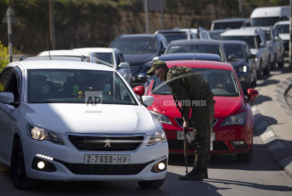 Majdi Mohammed Palestinian security forces stop vehicles, during a lockdown and quarantine measures, at an entrance to the the West Bank city of Ramallah, Sunday, March 7, 2021. Ramallah is under a strict lockdown for one week due to a surge in COVID-19 cases. (AP Photo/Majdi Mohammed)