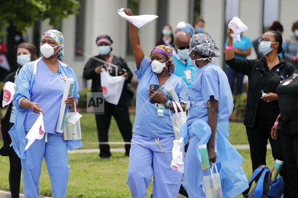 FILE - In this May 15, 2020, file photo, healthcare workers at New Orleans East Hospital wave handkerchiefs and dance to a jazz serenade, as a tribute for their care for COVID-19 patients, by the New Orleans Jazz Orchestra, outside the hospital in New Orleans. An act of generosity or self-sacrifice. A whimsical gesture to distract neighbors from anxiety or cabin fever. A helping hand to a person thrown out of a job, support for a patient struggling with COVID-19, solidarity with the medical professional toiling day and night to save them. Nearly three months later, there's been no end to the tales of good deeds we've found. (AP Photo/Gerald Herbert, File)