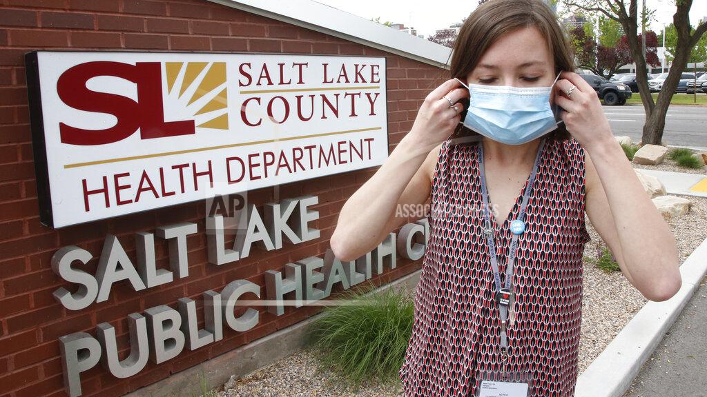 FILE - In this May 19, 2020, file photo, health investigator Mackenzie Bray adjusts her mask at the Salt Lake County Health Department in Salt Lake City. Contact tracers around Utah’s capital of Salt Lake City have seen caseloads double and cooperation wane since government leaders reopened the economy, Bray said. (AP Phoo/Rick Bowmer, File)