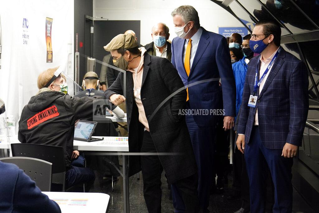 Richard Drew Actor Lin-Manuel Miranda, second left, greets a vaccination site worker, left, as he and New York Mayor Bill de Blasio, third left, tour the grand opening of a Broadway COVID-19 vaccination site intended to jump-start the city's entertainment industry, in New York, Monday, April 12, 2021. (AP Photo/Richard Drew, Pool)