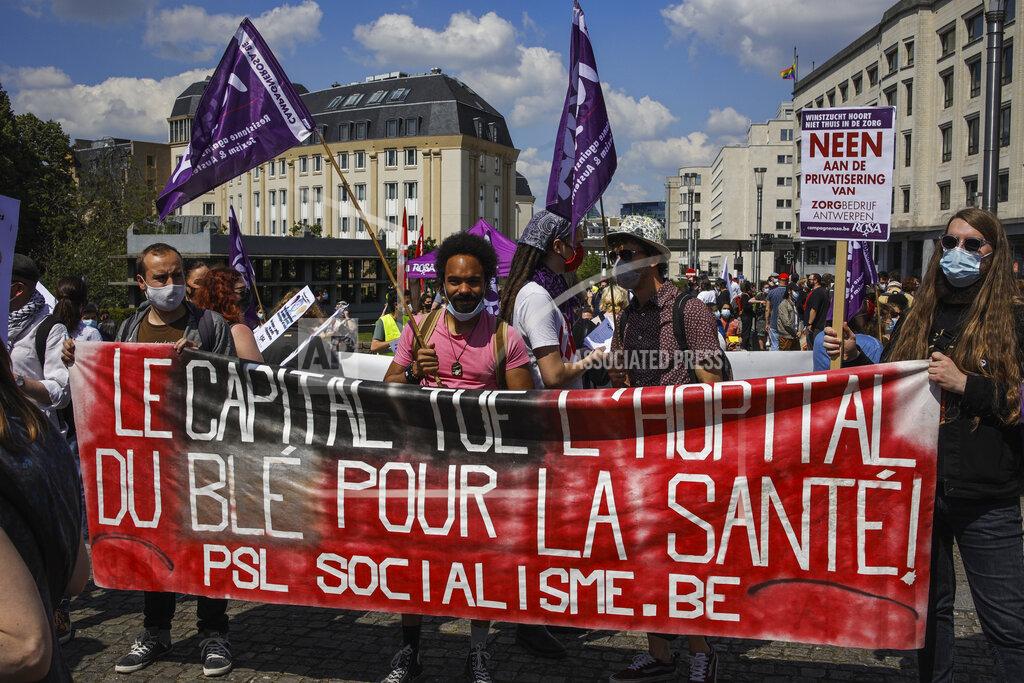 Olivier Matthys People hold a banner that reads in French: "Capital kills hospital. Money for the healthcare system!" during a healthcare workers' protest in downtown Brussels, Saturday, May 29, 2021. Protesters gathered to defend the healthcare system services and demanded more workers, better work conditions and bigger budged. (AP Photo/Olivier Matthys)