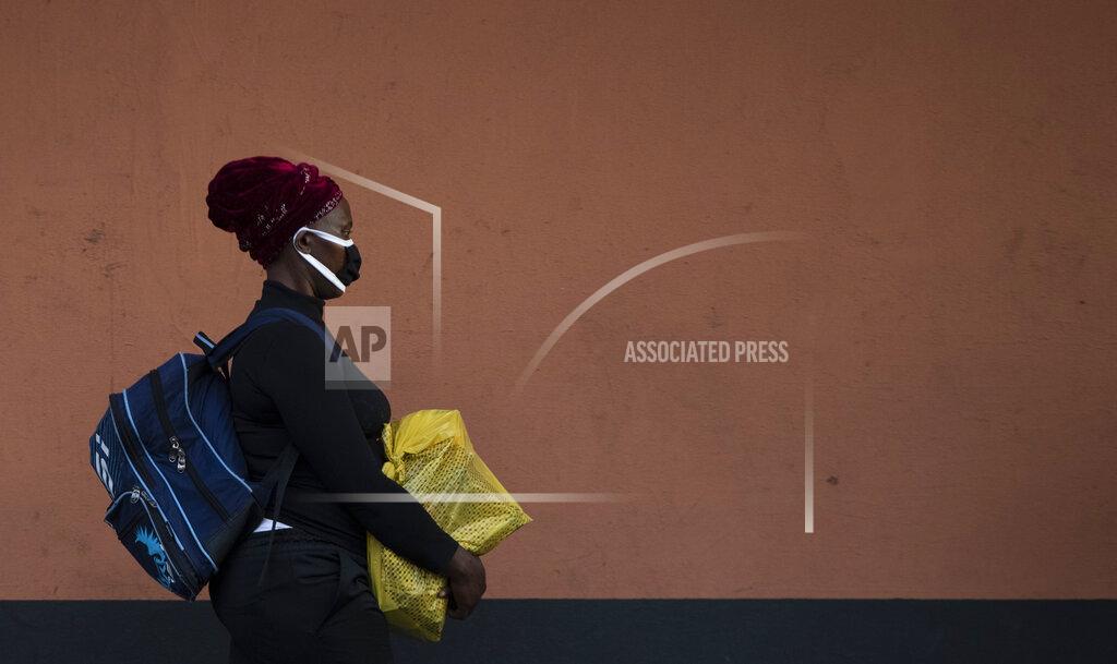 Themba Hadebe A woman, wearing a protective mask as a precaution against the spread of the new coronavirus, carries her shopping as she walks on the street in Johannesburg, South Africa, Wednesday, March 25, 2020, before the country of 57 million people, will go into a nationwide lockdown for 21 days from Thursday to fight the spread of the new coronavirus. The new coronavirus causes mild or moderate symptoms for most people, but for some, especially older adults and people with existing health problems, it can cause more severe illness or death. (AP Photo/Themba Hadebe)