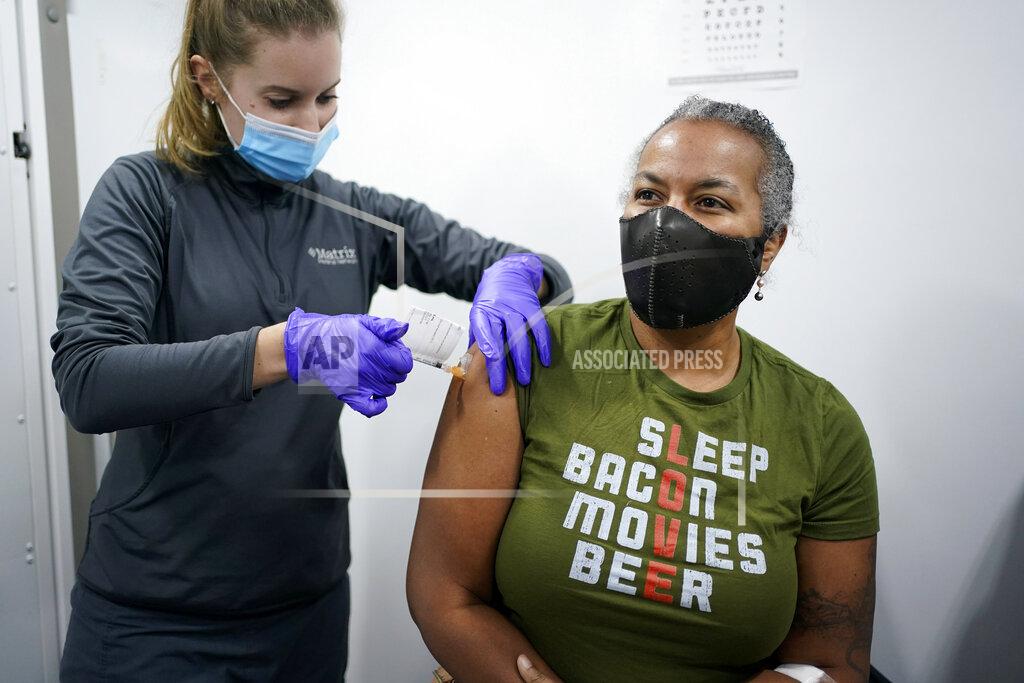 Seth Wenig Nurse Brianne Stockman, left, injects study participant Lani Muller with either a COVID-19 vaccine or a placebo in a mobile medical unit parked in the Queens borough of New York, Tuesday, Jan. 5, 2021. With more vaccines in the pipeline, scientists worry whether enough volunteers will join and stick with the testing needed to prove if they, too, really work. To help, researchers in more than a dozen spots around the country are rolling out mobile health clinics to better reach minority participants and people in rural areas who might not otherwise volunteer. (AP Photo/Seth Wenig)