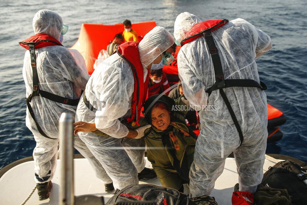 Emrah Gurel Turkish coast guard officers wearing protective gear to help prevent the spread of coronavirus, carry a woman off a life raft during a rescue operation in the Aegean Sea, between Turkey and Greece, Saturday, Sept. 12, 2020. Turkey is accusing Greece of large-scale pushbacks at sea — summary deportations without access to asylum procedures, in violation of international law. The Turkish coast guard says it rescued over 300 migrants "pushed back by Greek elements to Turkish waters" this month alone. Greece denies the allegations and accuses Ankara of weaponizing migrants. (AP Photo/Emrah Gurel)