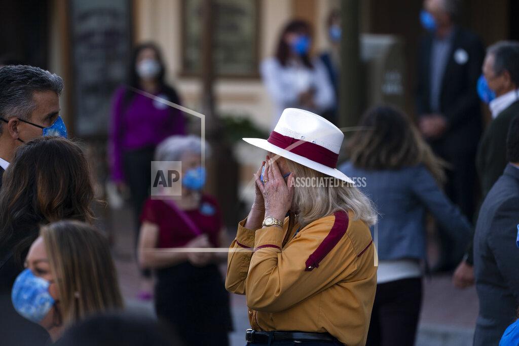 Jae C. Hong Employee Diane, who only gave her first name, wipes her tears after a flag raising ceremony at Disneyland in Anaheim, Calif., Friday, April 30, 2021. The iconic theme park in Southern California that was closed under the state's strict virus rules swung open its gates Friday and some visitors came in cheering and screaming with happiness. (AP Photo/Jae C. Hong)