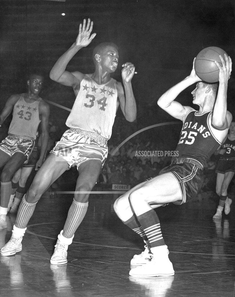 Frank Fisse FILE - In this March 13, 1954, file photo, Bobby Plump, right, of Milan High School, works the ball against Crispus Attucks' Willie Mason (34) and Oscar Roberston (43) during a high school basketball tournament semistate game at Hinkle Fieldhouse in Indianapolis. At age 84, the affable, silver-haired Plump remains one of the state's top basketball ambassadors and nothing, not a pandemic or an unprecedented NCAA Tournament, can keep those yearning to meet him away. (Frank Fisse/The Indianapolis Star via AP, File)