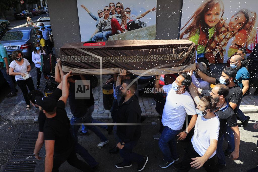 Hussein Malla Mourners carry the coffin of Ibrahim Harb, 35, who was critically injured in the massive explosion at Beirut's port last year and who died on Monday nearly 14 months after the blast, as other throw rice during his funeral procession in Beirut, Lebanon, Tuesday, Sept. 28, 2021. On Aug. 4, 2020, hundreds of tons of ammonium nitrate, a highly explosive material used in fertilizers, ignited after a massive fire at the port. The death brings to at least 215 the number of people who have been killed by the blast, according to official records. (AP Photo/Hussein Malla)