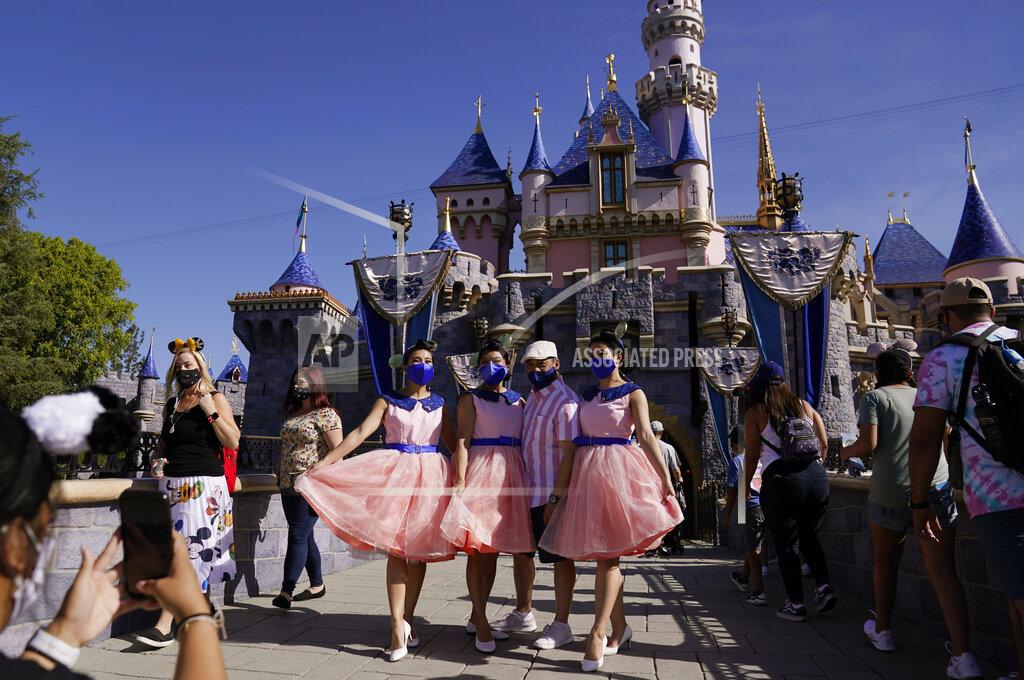 Jae Hong A family takes a photo in front of Sleeping Beauty's Castle at Disneyland in Anaheim, Calif., Friday, April 30, 2021. The iconic theme park in Southern California that was closed under the state's strict virus rules swung open its gates Friday and some visitors came in cheering and screaming with happiness. (AP Photo/Jae Hong)
