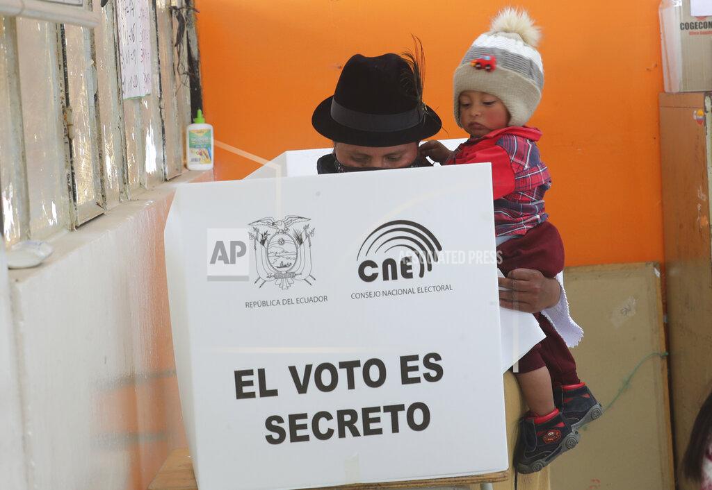 Dolores Ochoa A woman carries her son as she casts her ballot in a general election, in Cangahua, Ecuador, Sunday, Feb. 7, 2021. Amidst the new coronavirus pandemic, Ecuadoreans went to the polls in a first-round presidential and legislative election. (AP Photo/Dolores Ochoa)