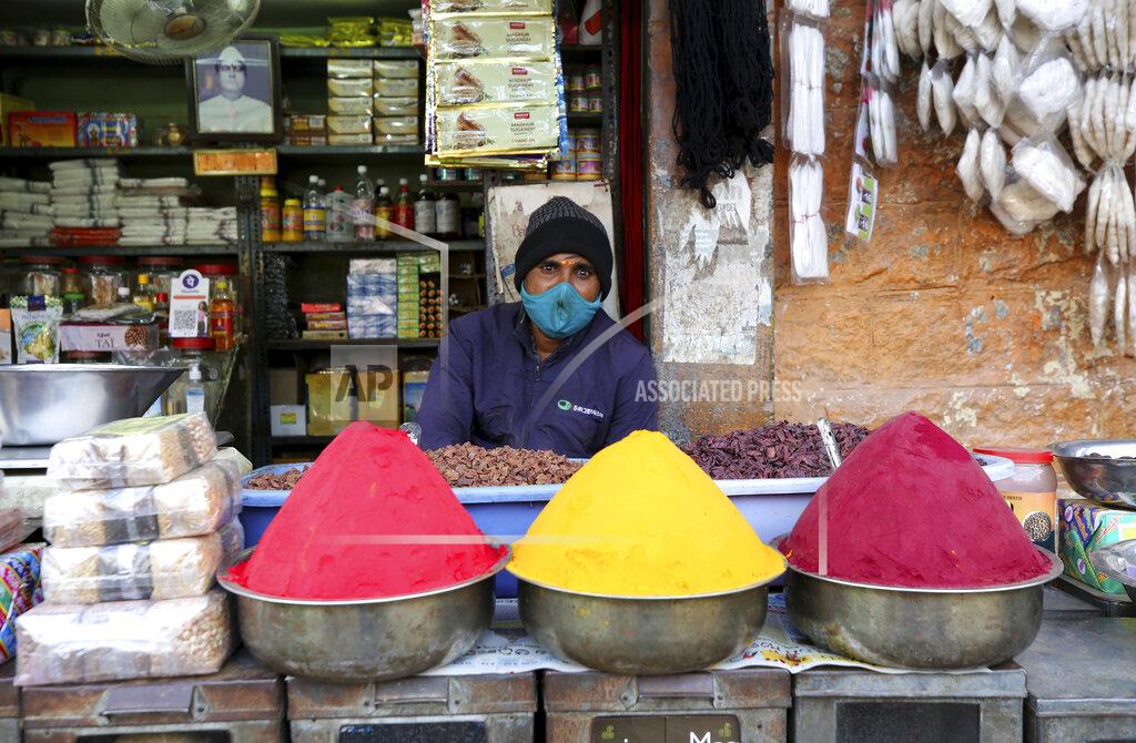 A shopkeeper wears a face mask as a precaution against the coronavirus waits for customers at a market in Bengaluru, India, Friday, Nov. 20, 2020. India's total number of coronavirus cases since the pandemic began has crossed 9 million. Nevertheless the country's new daily cases have seen a steady decline for weeks now and the total number of cases represents 0.6% of India's 1.3 billion population. (AP Photo/Aijaz Rahi)