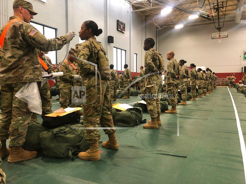 In this image provided by the U.S. Army, recent Army basic combat training graduates have their temperatures taken as they arrive at Fort Lee, Va, on March 31, 2020, after being transported using sterilized buses from Fort Jackson, S.C. COVID-19 has had a dramatic impact on military recruiting, shuttering enlistment stations around the country and forcing thousands of recruiters to woo potential soldiers online. Recruiters have had to abandon their normal visits to high schools and malls, and instead rely almost exclusively on social media to reach young people. (U.S. Army via AP)