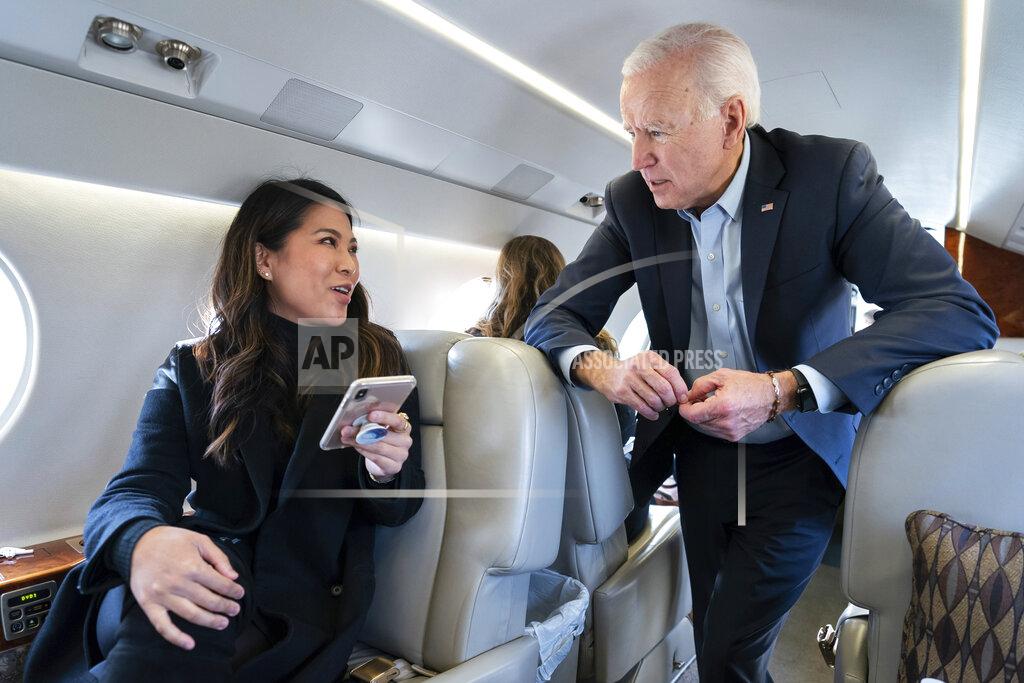 In this photo taken in November 2019, former Vice President Joe Biden speaks with his traveling national press secretary, Remi Yamamoto, on a flight to South Carolina. Richard Grenell, President Donald Trump's former ambassador to Germany and former acting director of national intelligence, tweeted this photo on Sunday, Nov. 1, 2020, alongside a photo of Biden standing outdoors while wearing a mask. The tweet, which claims that Biden wears a mask outside but doesn't wear one on his plane, creates the false impression that this photo of Biden without a mask was taken during the coronavirus pandemic. (Adam Schultz/Biden for President via AP)