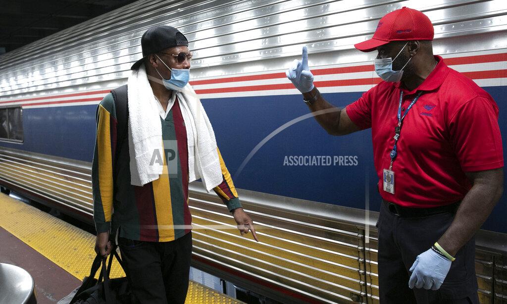 Mark Lennihan A traveler arriving on a train that originated in Miami gets directions from a porter, right, at Amtrak's Penn Station, Thursday, Aug. 6, 2020, in New York. Mayor Bill de Blasio is asking travelers from 34 states, including Florida where COVID-19 infection rates are high, to quarantine for 14 days after arriving in the city. (AP Photo/Mark Lennihan)