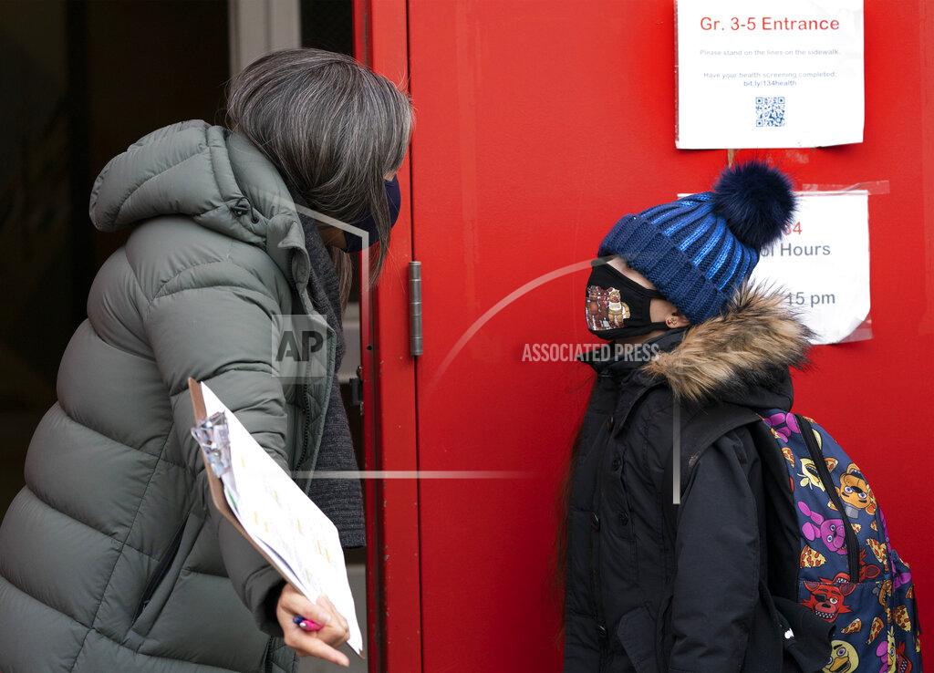 Mark Lennihan A school administrator, left, asks a student if his parents have completed a form granting permission for random COVID-19 testing as he arrives at P.S. 134 Henrietta Szold Elementary School, Monday, Dec. 7, 2020, in New York. Public schools reopened for in-school learning Monday after being closed since mid-November. (AP Photo/Mark Lennihan)
