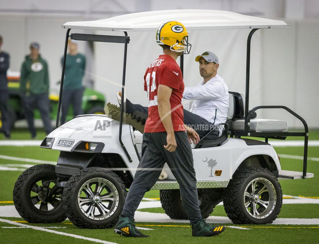 Mike Roemer Quarterback Aaron Rodgers, left, walks past head coach Matt LaFleur during an NFL football practice in Green Bay, Wisc., Wednesday, June 12, 2019. LeFleur is recovering from a torn Achilles. (AP Photo/Mike Roemer)