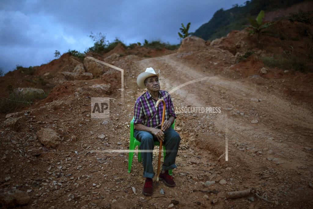 Rodrigo Abd Alejandro Mejia, 80, rests in a chair alongside a dirt road after a visit to the site where the home he built once stood, in the hillside community of La Reina, Honduras, Saturday, June 26, 2021. The home that Mejia and his wife had lived in for 48 years was buried in an epic mudslide triggered by heavy rains brought on by Hurricanes Eta and Iota in November 2020. (AP Photo/Rodrigo Abd)