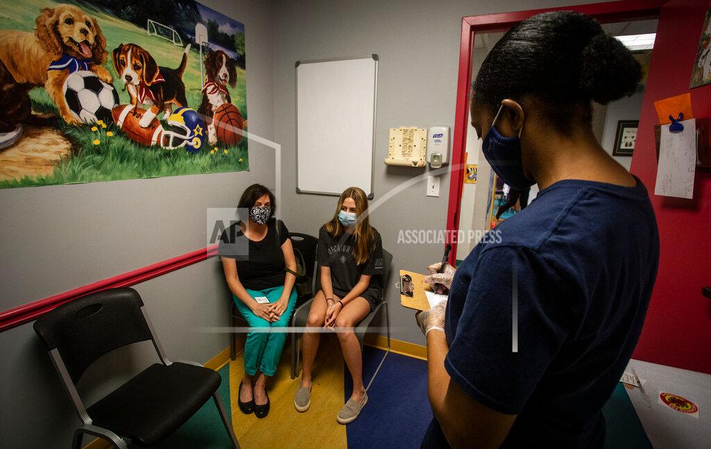 Ron Harris Middle school student Meredith Rogers, center, waits to receive her first coronavirus vaccination on Wednesday, May 12, 2021, in Decatur, Ga. Hundreds of children, ages 12 to 15, received the Pfizer vaccine at the DeKalb Pediatric Center, just days after it was approved for use within their age group. (AP Photo/Ron Harris)