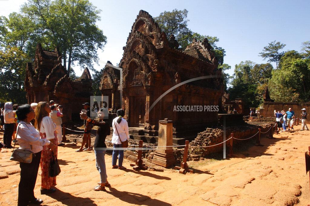 FILE - In this Dec. 23, 2017, file photo, tourists visit Banteay Srey temple outside Siem Reap, Cambodia. Cambodia is closing the Angkor temple complex to visitors because of a growing COVID-19 outbreak. On Thursday, April 8, 2021, the Health Ministry said 113 cases were reported from local transmission, with two deaths. The ministry traced the outbreak to a foreign resident who broke hotel quarantine to visit a nightclub. (AP Photo/Heng Sinith, File)