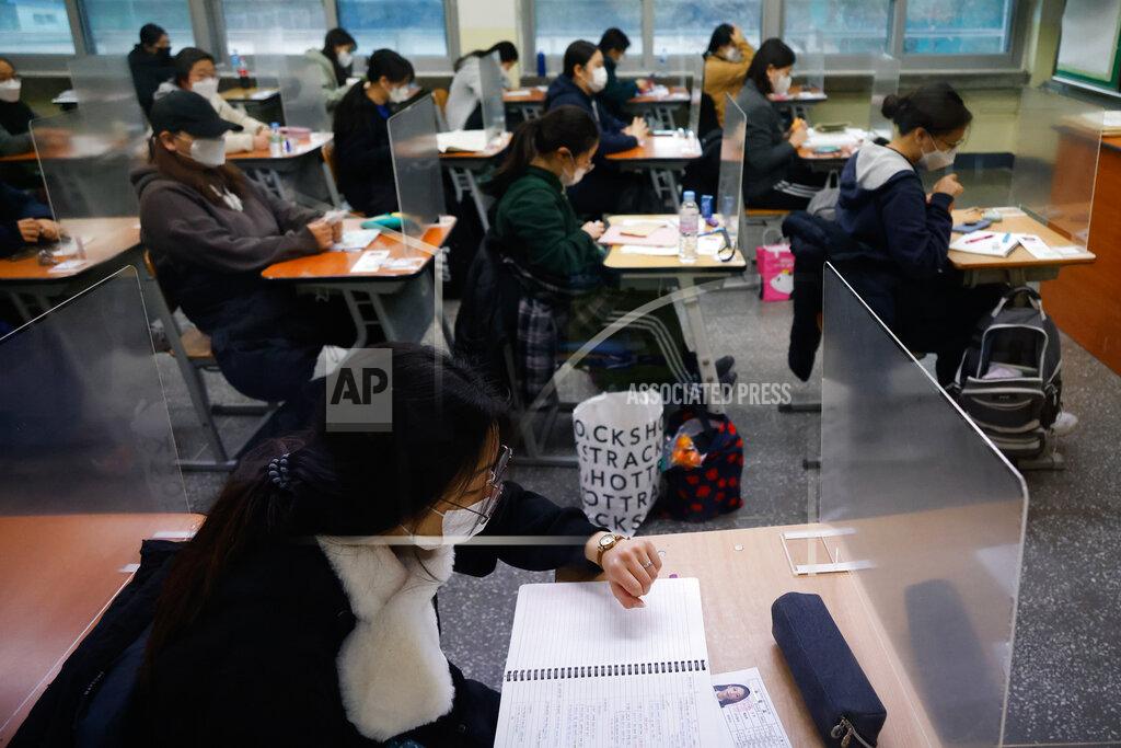 Kim Hong-Ji A student checks the time as others wait for the start of the annual college entrance examination amid the coronavirus pandemic at an exam hall in Seoul, South Korea, Thursday, Dec. 3, 2020. South Korean officials are urging people to remain at home if possible and cancel gatherings as about half a million students prepare for a crucial national college exam. (Kim Hong-Ji/Pool Photo via AP)