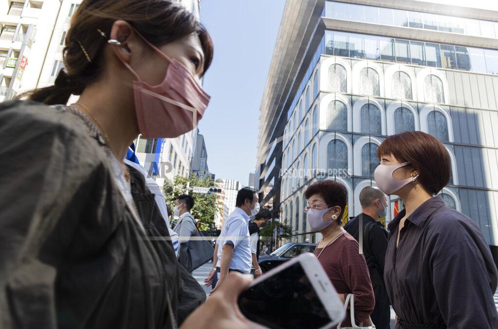 Hiro Komae People wearing face masks walk across an intersection in the Ginza shopping district in Tokyo on Thursday, June 10, 2021. (AP Photo/Hiro Komae)
