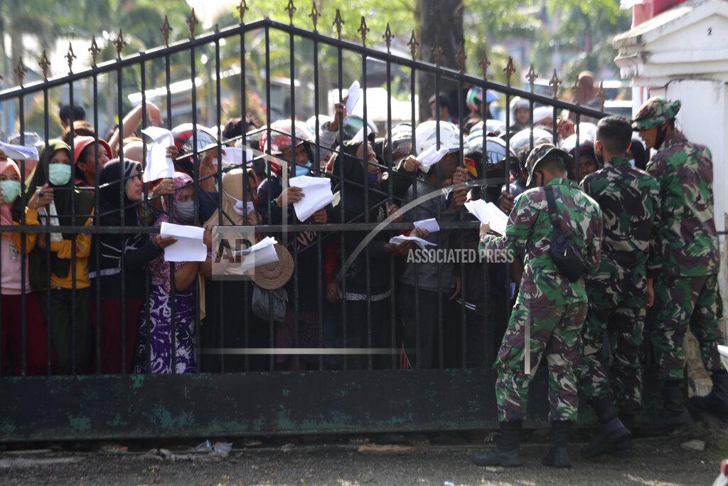 Joshua Marunduh People affected by earthquake queue up for relief goods in Mamuju, West Sulawesi, Indonesia, Monday, Jan. 18, 2021. Aid was reaching the thousands of people left homeless and struggling after an earthquake that killed a number of people in the province where rescuers intensified their work Monday to find those buried in the rubble. (AP Photo/Joshua Marunduh)