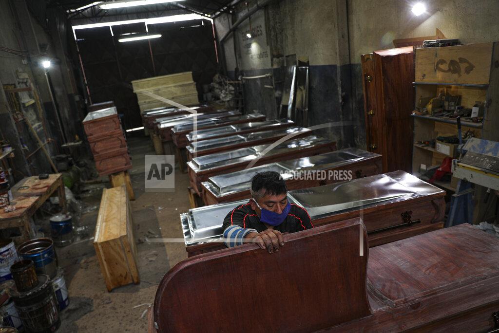 Esteban Felix Peruvian migrant coffin maker Cesar Ambrosio finishes the details on a production line of coffins at the Bergut Funeral Services in Santiago, Chile, Thursday, June 18, 2020. The coffin production has had to increase up to 120%, according to Nicolas Bergerie, owner of the factory. His more basic coffin model is called the COVID model and is made to cope with the increase of deaths during the coronavirus pandemic. (AP Photo/Esteban Felix)