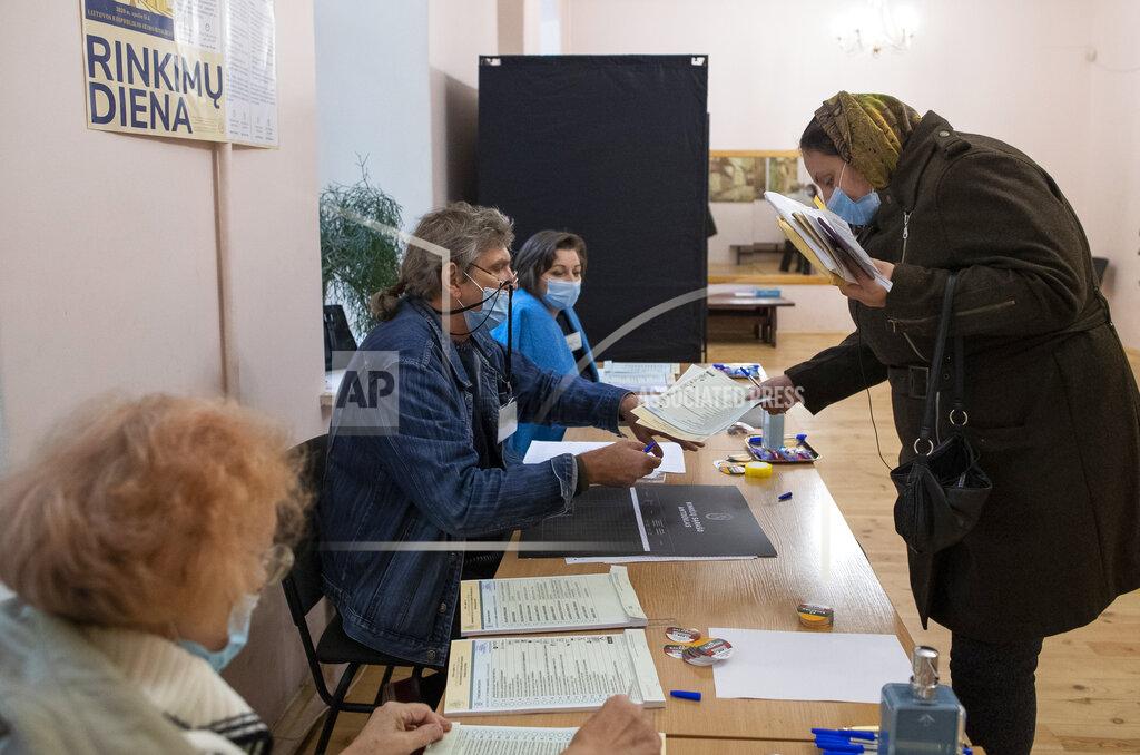 Mindaugas Kulbis A Lithuanian woman, wearing face mask to protect against coronavirus, arrives at a polling station during parliamentary elections in Vilnius, Lithuania, Sunday, Oct.11, 2020. Polls opened Sunday for the first round of national election in Lithuania, where voters will renew the 141-seat parliament and the ruling four-party coalition is widely expected to face a stiff challenge from the opposition to remain in office. (AP Photo/Mindaugas Kulbis)