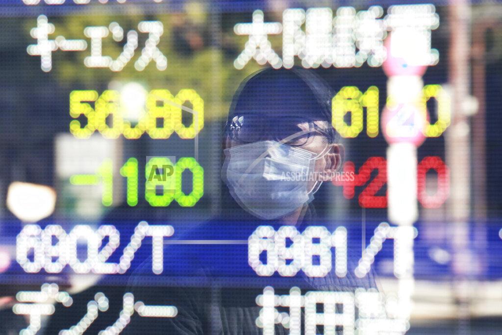Koji Sasahara A man is reflected on the electronic board of a securities firm in Tokyo, Wednesday, Jan. 20, 2021. Asian shares were mostly higher Wednesday, ahead of Joe Biden's inauguration as president, ending President Donald Trump’s four-year term. (AP Photo/Koji Sasahara)