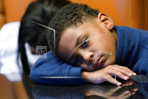In this Sept. 23, 2021, photo Jhaimarion, 10, reacts as he listens to his mother, Krystal Archie talking with an Associated Press reporter in Chicago. Archie’s three children were present when police, on two occasions, just 11 weeks apart, kicked open her front door and tore through their home searching for drug suspects. She’d never heard of the people they were hunting. Her oldest child, Savannah was 14 at the time; her youngest, Jhaimarion, was seven. They were ordered to get down on the floor. (AP Photo/Nam Y. Huh)