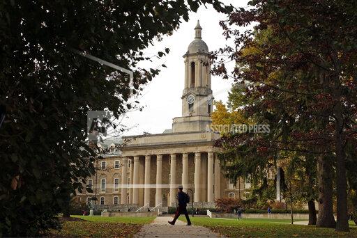 FILE- People walk by Old Main on the Penn State University main campus on Nov. 9, 2017 in State College, Pa. Applying to college is rarely easy, but applicants in 2022 are faced with one additional challenge: creating a compelling college application after nearly two years of disruptions as a result of the pandemic. (AP Photo/Gene J. Puskar, File)