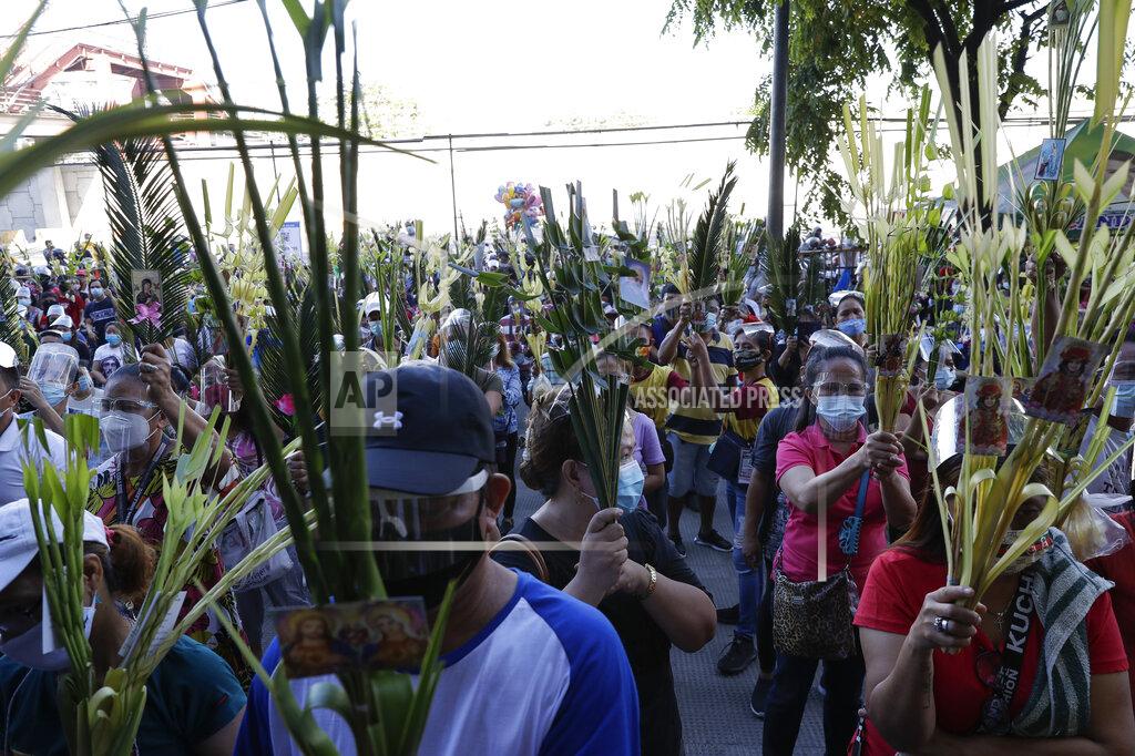 Aaron Favila Devotees wearing face masks and face shields to prevent the spread of the coronavirus attends a Palm Sunday mass, March 28, 2021 outside the Saint Peter Parish Church in Quezon city, Philippines. The government banned religious activities during the Holy Week as it enters into stricter lockdown measure starting next week while country struggles to control an alarming surge in COVID-19 cases. (AP Photo/Aaron Favila)