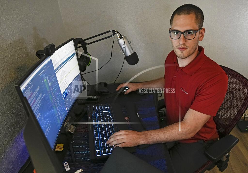 Steve Nesius In this Sept. 20, 2021, photo Austin Moody poses for a photo as he sits a his home work station in Tampa, Fla. Moody, the Michigan native, got a scholarship from the Department of Defense that required working for the agency at least a year after graduating. Moody said he understands that state governments don't have the kind of money that federal agencies or private companies spend on recruiting and generous salaries. (AP Photo/Steve Nesius)