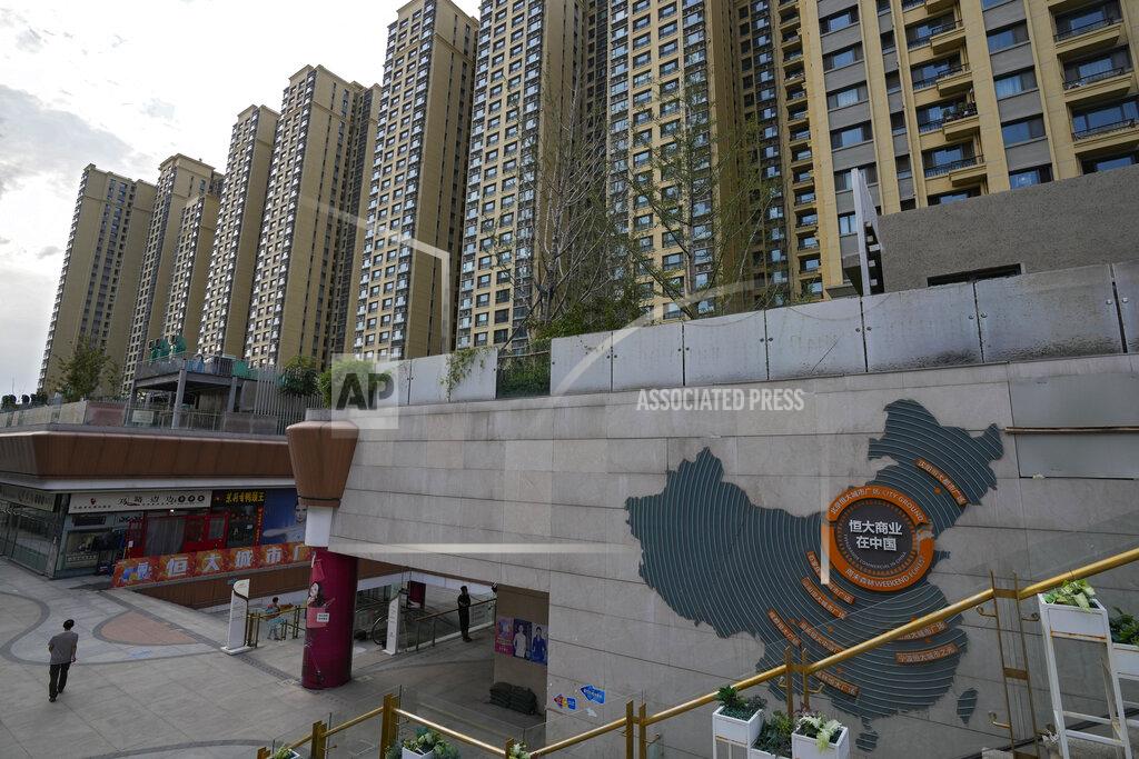 Andy Wong A man walks by a China's map showing Evergrande development projects and its apartment buildings are seen behind, at an Evergrande city plaza in Beijing, Wednesday, Sept. 15, 2021. One of China's biggest real estate developers is struggling to avoid defaulting on billions of dollars of debt, prompting concern about the broader economic impact and protests by apartment buyers about delays in completing projects. Rating agencies say Evergrande Group appears likely to be unable to repay all of the 572 billion yuan ($89 billion) it owes banks and other bondholders. That might jolt financial markets, but analysts say Beijing is likely to step in to prevent wider damage. (AP Photo/Andy Wong)