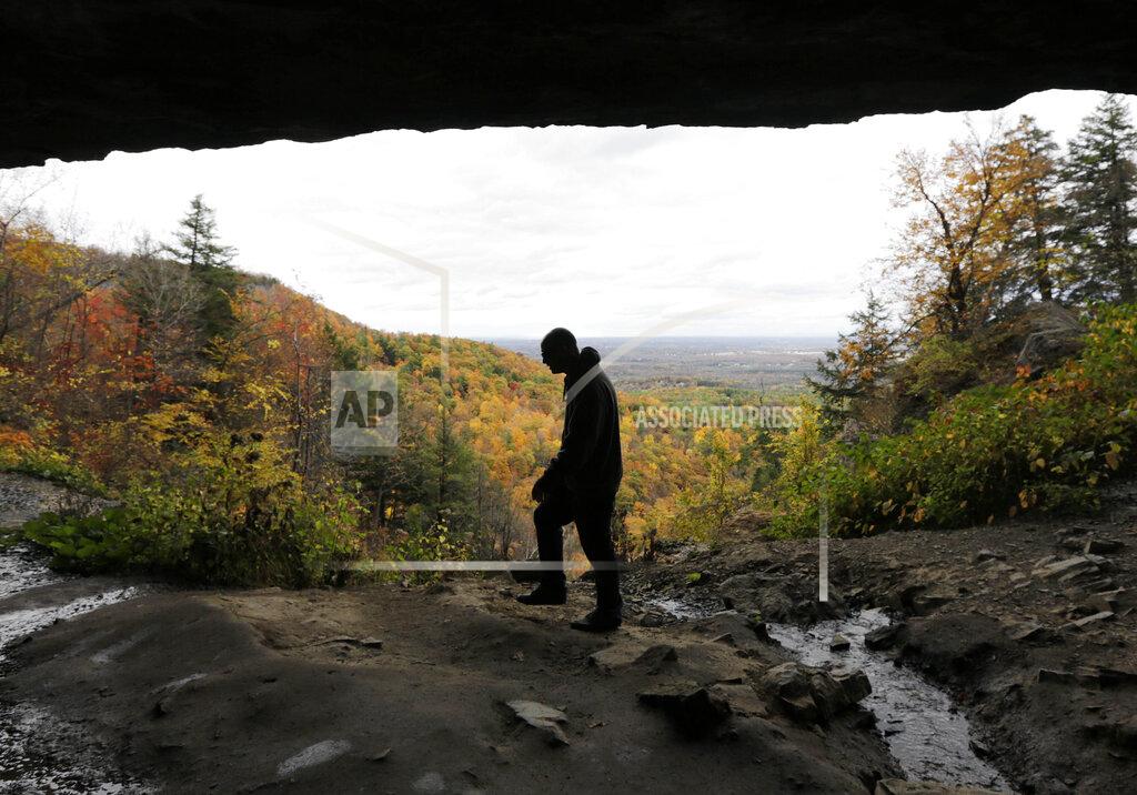 FILE- In this Oct. 18, 2013, file photo, Randy Thurston, of San Jose, Calif., takes in the fall foliage and the view of the Mohawk Valley while hiking with family and friends along the Indian Ladder Trail at Thacher State Park in Voorheesville, N.Y. Gov. Andrew Cuomo on Monday, May 11, 2020, gave the green light to several regions of the state not as severely affected by the outbreak to gradually re-start their economies once the latest stay-at-home order expires Friday. The Southern Tier, Mohawk Valley and the Finger Lakes have met all seven benchmarks for opening some business activity and need to work out some logistical details by the end of the week, Cuomo said. The North Country, which includes Essex County, is close behind. (AP Photo/Mike Groll, File)