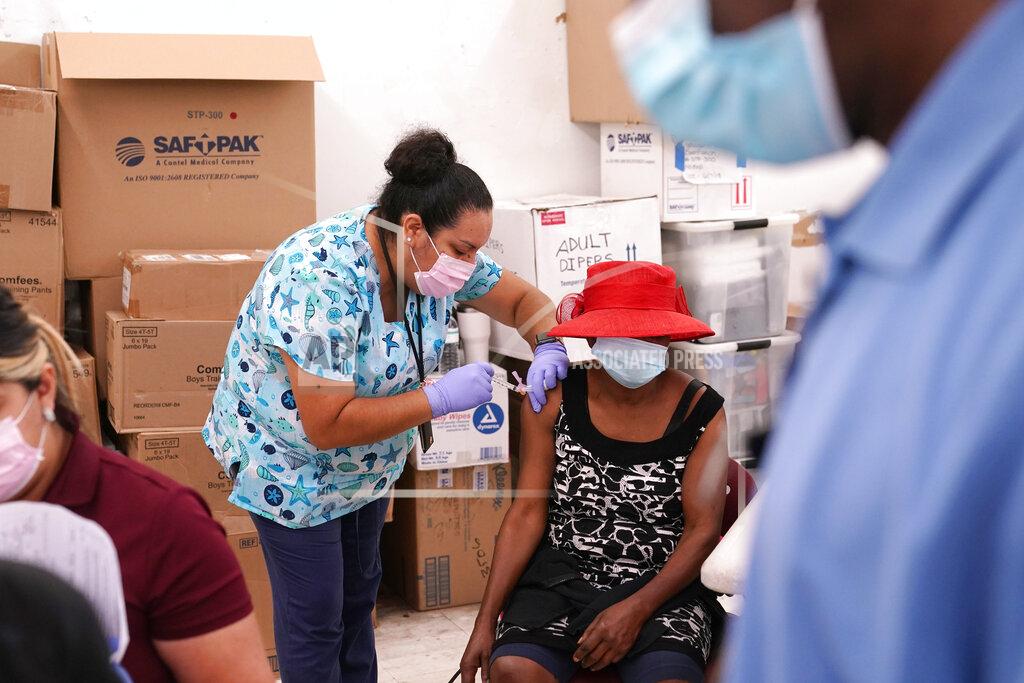 Lynne Sladky FILE - In this April 10, 2021, file photo, registered nurse Ashleigh Velasco, left, administers the Johnson & Johnson COVID-19 vaccine to Rosemene Lordeus, right, at a clinic held by Healthcare Network in Immokalee, Fla. Fewer Americans are reluctant to get a COVID-19 vaccine than just a few months ago, but questions about side effects and how the shots were tested still hold some back, according to a new poll that highlights the challenges at a pivotal moment in the U.S. vaccination campaign. (AP Photo/Lynne Sladky, File)