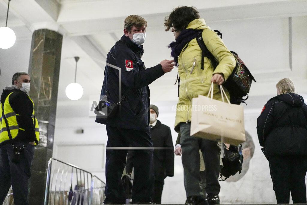 Pavel Golovkin Moscow's metro security personnel, center left, stops a passenger without a protective mask as she walks in the subway in Moscow, Russia, Monday, Oct. 25, 2021. Russia reported another daily record of confirmed coronavirus cases Monday as a surge in infections has prompted the Kremlin to tell most people to stay away from work starting later this week. (AP Photo/Pavel Golovkin)
