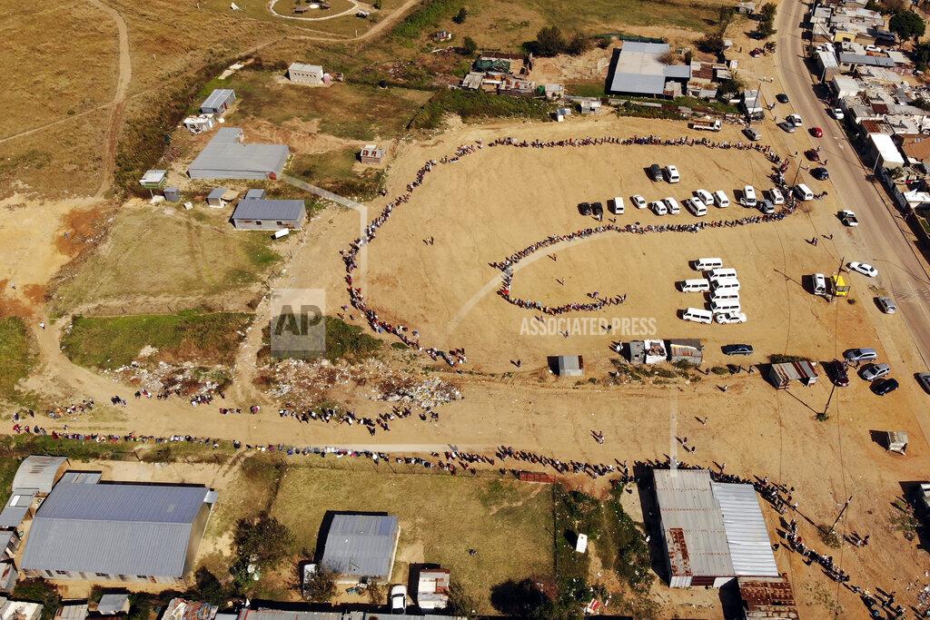 Jerome Delay FILE- In this drone file photo taken Saturday May 2, 2020, thousands line up to receive food handouts in the Olievenhoutbos township of Midrand, South Africa. South Africa is struggling to balance its fight against the coronavirus with its dire need to resume economic activity. The country with the Africa’s most developed economy also has its highest number of infections — more than 19,000. (AP Photo/Jerome Delay, File)