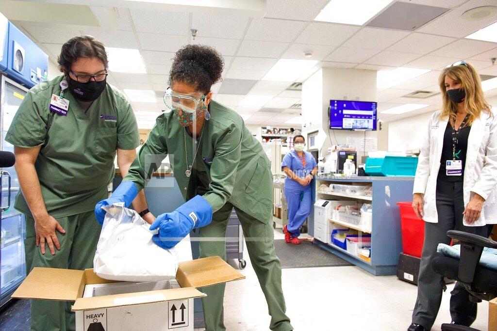 In this image provided by Christus St. Vincent Regional Medical Center, pharmacy staff members unpack the first shipment of COVID-19 vaccines at the hospital in Santa Fe, New Mexico, on Monday, Dec. 14, 2020. The medical center was the first in New Mexico to receive doses as hospitals elsewhere around the state prepared for deliveries later this week. (Christus St. Vincent Regional Medical Center via AP)