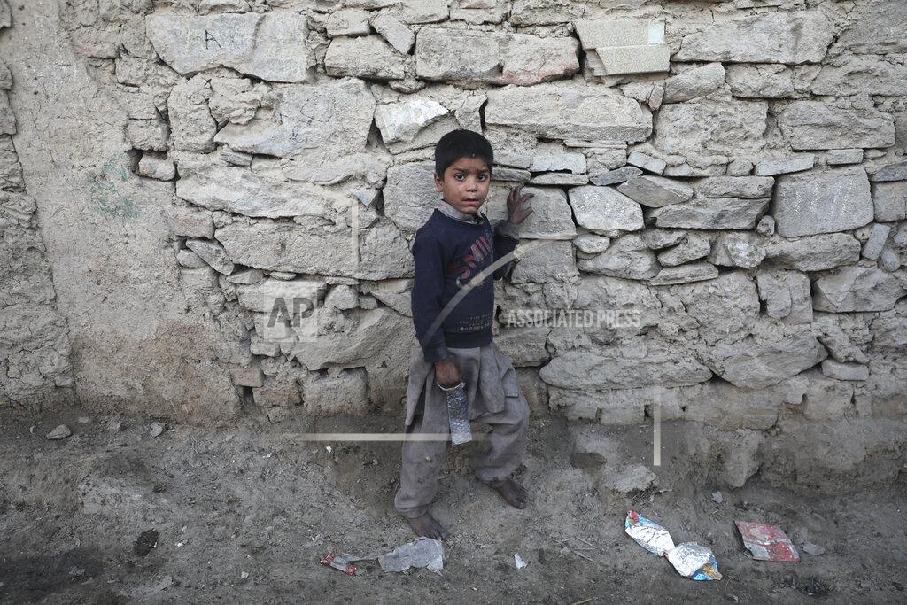 Rahmat Gul An internally displaced boy pose for a photograph outside his temporary home in the city of Kabul, Afghanistan, Wednesday, Dec. 30, 2020. Save the Children has warned that more than 300,000 Afghan children face freezing winter conditions that could lead to illness, in the worst cases death, without proper winter clothing and heating. (AP Photo/Rahmat Gul)